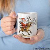 "Get Off Me You Fat Cunt" - Christmas Mug featuring Santa and Rudolph held by woman in blue jumper