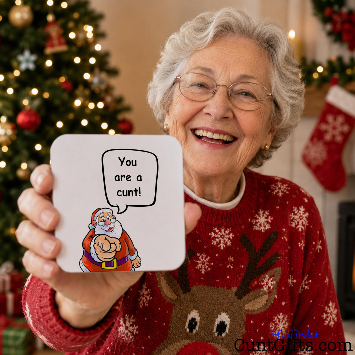 Santa says your a cunt drink coaster held by laughing elderly woman in Christmas jumper with tree in background.