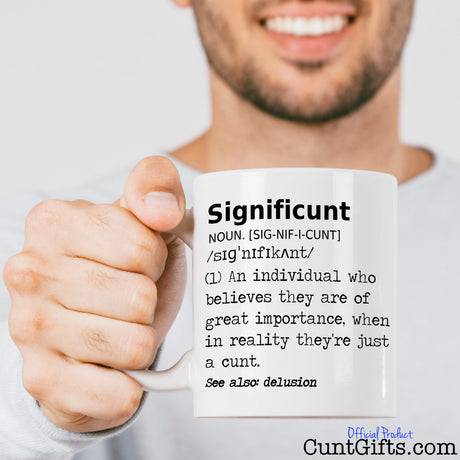 Significunt Mug held out by smiling man with stubble in a white long sleaved t-shirt.