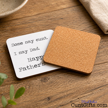 Some say cunt I say Dad - Father's Day Drink Coaster. Both sides showing on wooden table with plant.