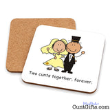 Two square cork drink coasters shown on a white background, with one coaster upright and the other leaning behind it. The front coaster is white with a cartoon bride and groom illustration and the text 'Two cunts together, forever.