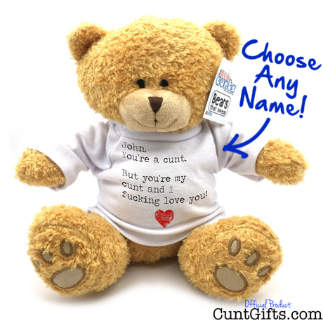 A plush teddy bear sitting against a white background, wearing a white T-shirt with printed black text and a small red heart. A hangtag on the ear reads 'Custom Cuddly Bears' and there is blue handwritten text saying 'Choose Any Name!' with an arrow pointing to the shirt.