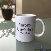 Happy Birthday You Cunt - Mug on Glass Table