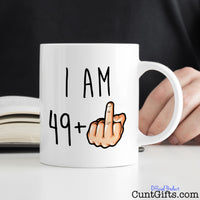 I am any age + Fuck You Mug on desk with book